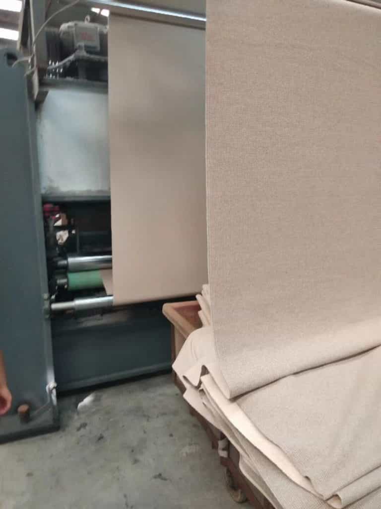 A close-up of a stack of double-face wool fabric swatches in various colors, showing the textured knit